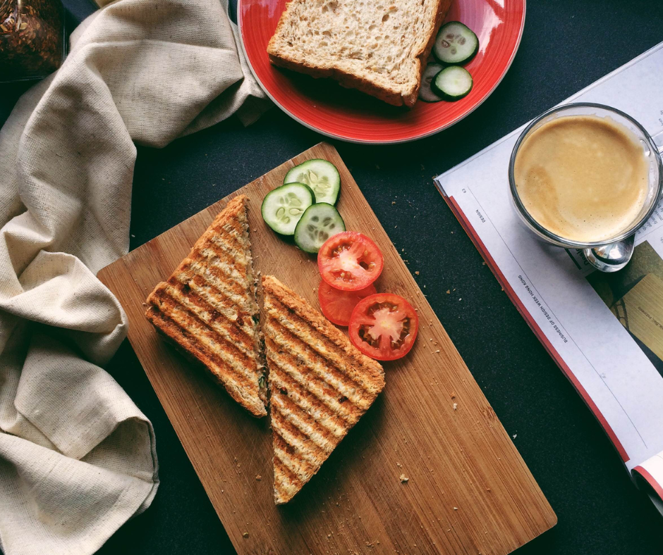 A birds eye shot of a simple sandwich and a cup of coffee on a dining table.